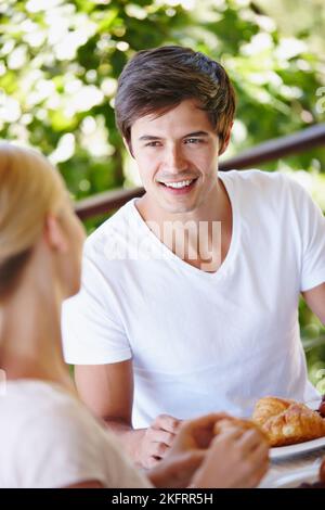 Es ist einfach besser und heller beim Frühstück. Ein glückliches junges Paar, das zu Hause auf der Terrasse zusammen frühstückt. Stockfoto