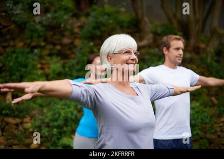 Nie zu alt, um Neues zu lernen. Eine ältere Frau genießt einen Yoga-Kurs im Freien. Stockfoto