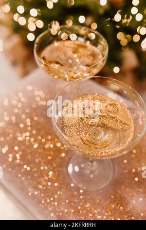 Hintergrund der Silvesterfeier 2022-2023 mit Champagner. Sektgläser auf Glitzerhintergrund. Weihnachtsschmuck. Stockfoto