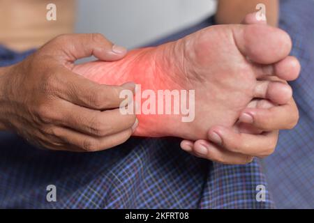 Juckende Fußhaut des asiatischen jungen Mannes. Konzept von Hauterkrankungen wie Krätze, Pilzinfektionen, Hautausschlag, Allergie, etc. Stockfoto