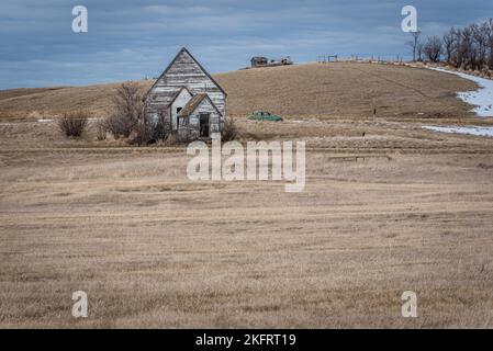 Neidpath, Saskatchewans alte, verlassene weiße Kirche mit einem klassischen, verlassenen Auto auf einem schneebedeckten Hügel Stockfoto
