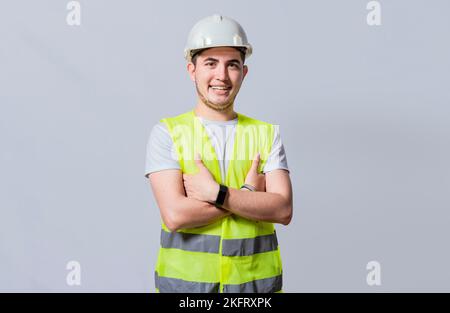 Porträt eines lächelnden, gutaussehenden Ingenieurs auf weißem Hintergrund, Porträt eines jungen Ingenieurs, der Helm und Weste isoliert trägt. Junger lächelnder Ingenieur trägt Stockfoto