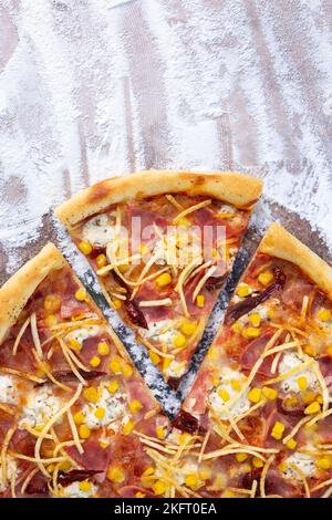 Ein Stück wird von der Pizza-Draufsicht abgeschnitten. Foto für Pizza-Werbung. Stockfoto