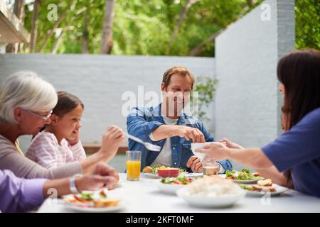 Lets Eat. Eine glückliche, generationsübergreifende Familie, die draußen zusammen essen kann. Stockfoto