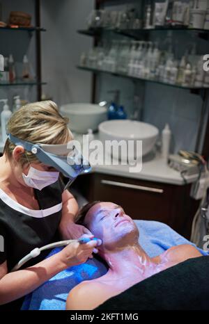 Mit einer Laserbehandlung Magie auf seiner Haut. Ein Mann, der in einer Schönheitsklinik eine nicht-invasive Gesichtsstraffung erhält. Stockfoto