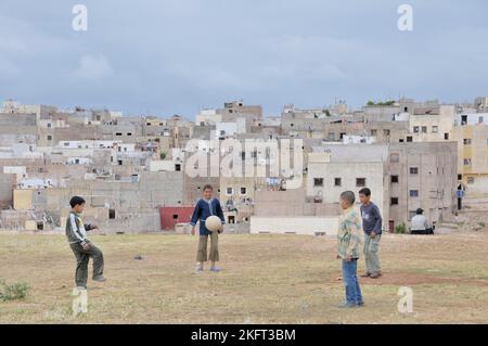 Jungen spielen Fußball, hinter ihnen Häuser und Wohnungen der ärmeren Bevölkerung, Siedlung außerhalb Fes, Marokko, Afrika Stockfoto