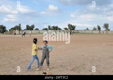 Mädchen als Zuschauer, Männer, die Fußball spielen, Besiedlung der ärmeren Bevölkerung außerhalb Fes, Marokko, Afrika Stockfoto