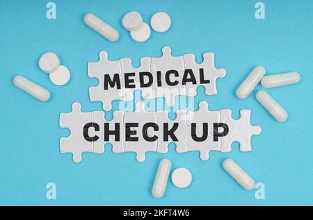 Medizinkonzept. Auf blauem Hintergrund Pillen und Puzzles mit der Aufschrift - ÄRZTLICHE ÜBERPRÜFUNG Stockfoto