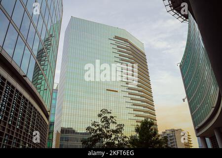 Unter den modernen Bürohochhäusern mit verspiegelten Glasfassaden, die den Himmel im Sonnenuntergang reflektieren Stockfoto