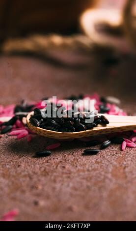 Nahaufnahme weicher Fokus von Holzlöffel mit einem Haufen frischen schwarzen Reis auf den Tisch in der Küche gelegt Stockfoto