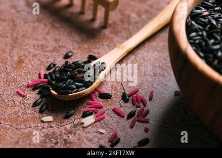 Nahaufnahme weicher Fokus von Holzlöffel mit einem Haufen frischen schwarzen Reis auf den Tisch in der Küche gelegt Stockfoto