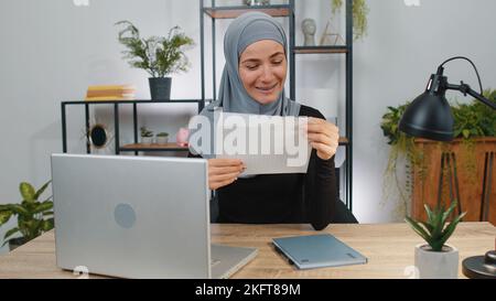 Glückliche muslimische Frau offen lesen Briefumschlag Brief. Karriere Wachstum Förderung, Bankkredit genehmigen, erfolgreiche Zulassung zur Universität Geldpreis lang erwartete Einladung große Nachrichten, Lotterie Spiel gewinnen Stockfoto