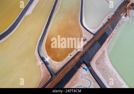 Von oben aus Luftaufnahme einer geraden Straße in der Nähe von Salzwasserverdampfungsteichen in den USA Stockfoto