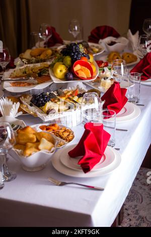 Der Tisch im Zimmer ist in Rottönen mit Essen für den Urlaub eingestellt Stockfoto