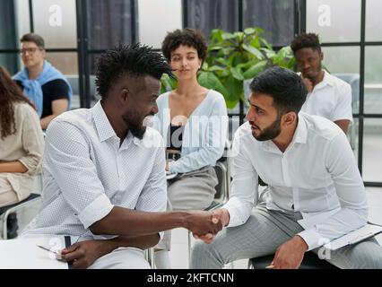 Positive, multiethnische Geschäftsleute in formeller und legerer Kleidung diskutieren über ein Forum Stockfoto