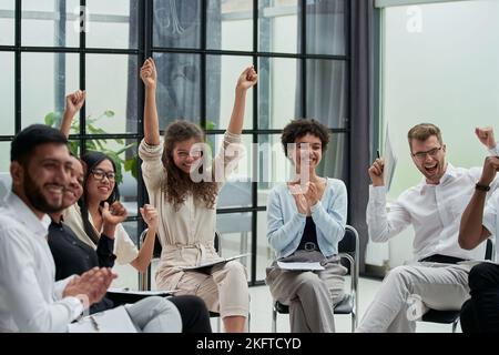 Geschäftsleute mit erhobenen Armen während des Seminars Stockfoto