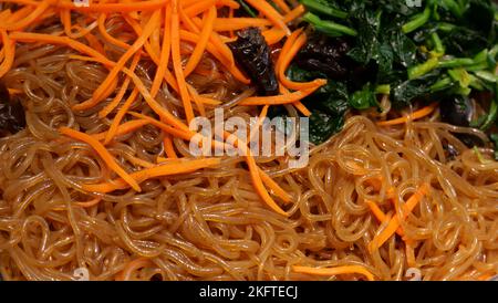 Hintergrund asiatischer Speisen im Vollformat mit Nudeln, Karotten und Spinat Stockfoto