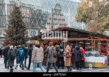 19-11-2022 BUDAPEST, UNGARN: Besucher des Weihnachtsmarktes oder der Messe im Stadtzentrum, riesiger weihnachtsbaum mit roten Ornamenten und Ständen Stockfoto