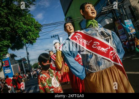 Angono, Rizal, 20. November 2022. Papiermaché-Statuen wandern während der großen Parade des Higantes-Festivals am 20. November 2022 durch die Straßen von Angono, Rizal. Nach einer zweijährigen Pause aufgrund der Pandemie feiern die Einheimischen zum ersten Mal das Fest ihrer Stadt. Die Higantes, oder Papiermaché-Riesen, wurden vermutlich von lokalen Bauern während der spanischen Kolonisationszeit als eine Form des Protests gegen ihre Hauswirte geschaffen. Die riesigen Pappmaché-Puppen haben eine Größe von vier bis fünf Fuß im Durchmesser und zehn bis zwölf Fuß in der Höhe, und sie können nur von innen aus gesteuert werden. Stockfoto