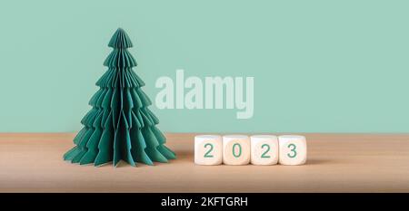 Holzwürfel mit der Jahresnummer 2023 in der Nähe von Papier als Weihnachtsbaumschmuck. Stockfoto