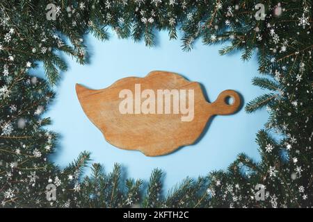 Schneidebrett liegt auf einem Hintergrund von grünen Weihnachtsbaum Äste. Rahmen aus Tannenzweigen und Tannenzapfen. Neujahrs- und Weihnachtskonzept.Top vie Stockfoto
