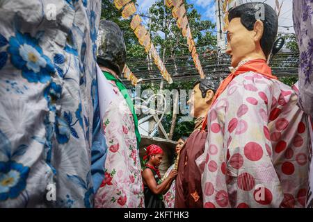 Angono, Philippinen, 20/11/2022, Ein Mann sah, wie er während der großen Parade des Higantes-Festivals eine Pappmaché-Statue anzog. Die Einheimischen feiern das Fest ihrer Stadt zum ersten Mal nach zwei Jahren der Suspendierung aufgrund der Pandemie. Die Higantes- oder Pappmaché-Giganten wurden zuerst als eine Form des Protests gegen ihre Gutsbesitzer während der spanischen Kolonisationszeit von lokalen Bauern gemacht. Die riesigen Pappmaché-Puppen messen einen Durchmesser von vier bis fünf Fuß und eine Höhe von zehn bis zwölf Fuß und können die Riesen nur von innen aus kontrollieren. Stockfoto