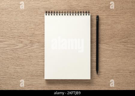Notizbuch und schwarzer Bleistift auf Eichenschreibtisch. Flach liegend. Draufsicht Stockfoto