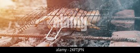 Huhn Fleisch Essen gebraten Grill auf schwelende Kohlen oder Ember vom Lagerfeuer auf dem Boden am Sommer oder Herbsttag. Grill in Camping-Bedingungen. Überleben o Stockfoto