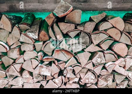 Trockene gehackte Brennholzstämme auf einem Stapel in Innenräumen. Ein Haufen Brennholz, um den Kamin zu befeuern Stockfoto
