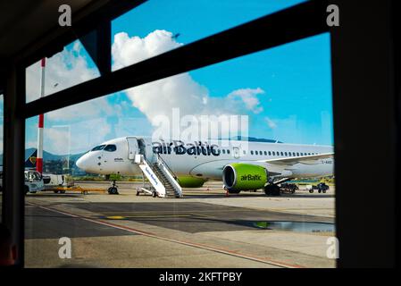 Kerkyra, Griechenland - 09 29 2022: Blick vom Fenster des Korfu-Flughafens auf dem grünen Flugzeug von AirBaltic. Parkplatz Für Flugzeuge, Flugzeug Ist Mit Gepäck Beladen Stockfoto