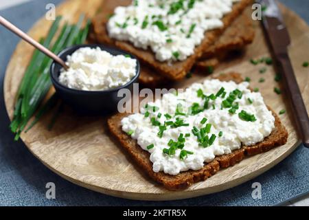 Offene Sandwiches mit Roggenbrot und weißem Quark mit grünen Zwiebeln. Gesundes Frühstück oder Snack. Stockfoto