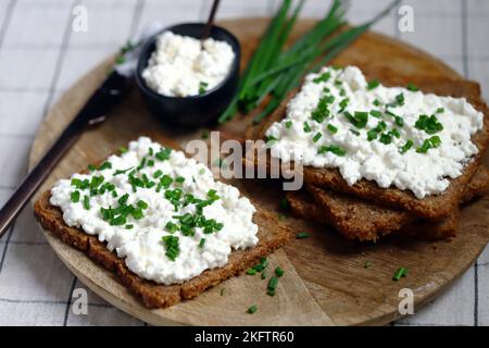 Offene Sandwiches mit Roggenbrot und weißem Quark mit grünen Zwiebeln. Gesundes Frühstück oder Snack. Stockfoto