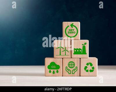 Null-CO2-Emissionen und CO2-neutrales Konzept. Holzwürfel mit Netto-Null-Symbolen für erneuerbare Energie, emissionsreduzierung CO2, grüne Produktion Stockfoto