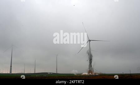 20. November 2022, Nordrhein-Westfalen, Jüchen: Eine Windkraftanlage stürzt bei einer Sprengung aufgrund von Baufehlern ein. Aufgrund schwerer Schäden am Betonturm wurde die neue Windenergieanlage mit einer Nabenhöhe von 164 Metern gesprengt. Die Turbine war Teil des Windparks Jüchen A44n. Foto: Henning Kaiser/dpa Stockfoto