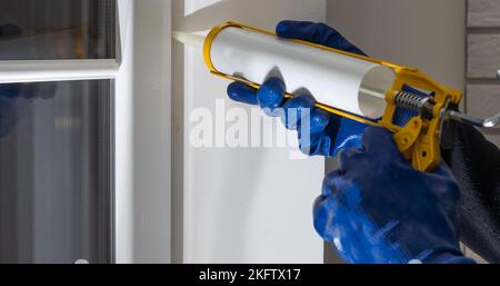 Bauarbeiter versiegelt Fenster mit Versiegelung in Innenräumen Stockfoto