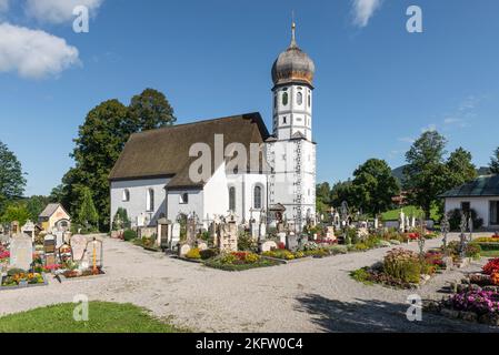 Die barocke katholische Kirche zum Schutz der Jungfrau Maria, umgeben von Gräbern des Friedhofs Fischbachau, Bayern, Deutschland Stockfoto