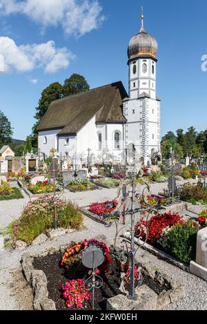 Die barocke katholische Kirche zum Schutz der Jungfrau Maria, umgeben von Gräbern des Friedhofs Fischbachau, Bayern, Deutschland Stockfoto