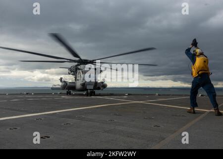 Ryan Akerson, ein Bootsmann auf der U.S.N.S Sacagawea, leitet eine CH-53E Super Henglion Marine Heavy Helicopter Squadron 361, Marine Aircraft Group 16, 3. Marine Aircraft Wing, auf das Landedeck des United States Naval Ship Sacagawea im Kushiro Port, Japan, 8. Oktober 2022. Die U.S.N.S Sacagawea dient als Kommandooperationszentrum für das Combat Logistics Regiment 37 und bietet logistische Unterstützung für verschiedene Einheiten, die an Resolute Dragon teilnehmen. Resolute Dragon 22 ist eine jährliche Übung zur Stärkung der Verteidigungsfähigkeit des US-japanischen Bündnisses durch die Ausübung von Integrat Stockfoto