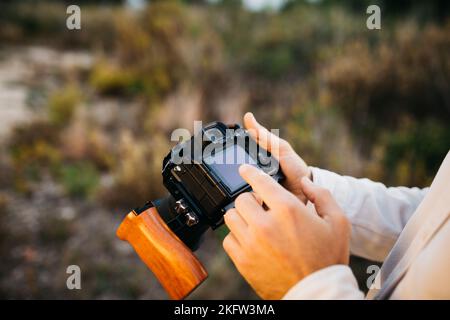 Nahaufnahme der Hände eines Mannes mit seiner Digitalkamera auf dem Land Stockfoto