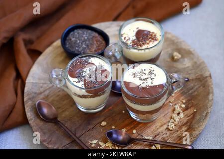 Gesunde Desserts in Tassen. Pudding aus Vanille und Schokolade mit Chiasamen und Leinsamen. Stockfoto