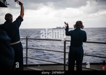 221010-N-WI365-1010 PHILIPPINISCHES MEER (OKT 10, 2022) Matrosen, die dem einzigen vorwärts eingesetzten Flugzeugträger der US-Marine, USS Ronald Reagan (CVN 76), zugewiesen wurden, winken dem Zerstörer JS Asahi (DD 119) der Japan Maritime Self-Defense Force (JMSDF), der am 10. Oktober am Schiff in der philippinischen See vorbei fährt. Ronald Reagan, das Flaggschiff der Carrier Strike Group 5, stellt eine kampfbereite Kraft zur Verfügung, die die Vereinigten Staaten schützt und verteidigt und Allianzen, Partnerschaften und kollektive maritime Interessen in der Indo-Pazifik-Region unterstützt. Stockfoto