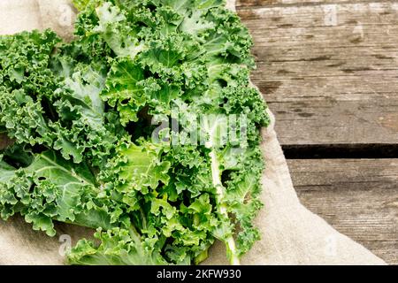 Natürliches Gemüse für Salat. Bio-Grünkohlblätter auf einem Holztisch. Umweltfreundliche, vegane oder vegetarische Speisen. Lokal angebaut, Landwirt, Bio Stockfoto