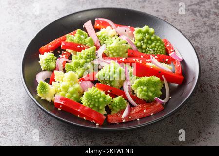 Konzept der gesunden Ernährung Essen Salat mit Romaneskokokohl, Paprika und roten Zwiebeln Nahaufnahme auf dem Teller auf dem Tisch. Horizontal Stockfoto