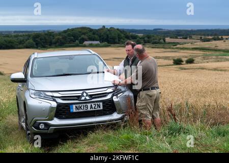 Landagent und Landwirt, der sich auf einen Pickup stützte, diskutierten über die Betriebsführung auf einem Ackerbaubetrieb in Northumberland, Großbritannien. Stockfoto