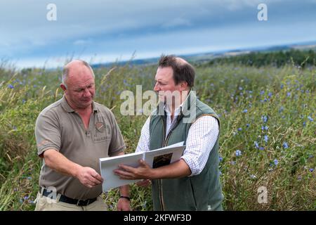 Landagent und Landwirt diskutieren über die Betriebsführung auf einem Ackerbaubetrieb in Northumberland, Großbritannien. Stockfoto