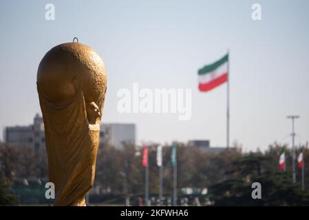 Teheran, Iran. 18.. November 2022. Die Skulptur der FIFA-WM-Trophäe ist neben der iranischen Flagge vom Azadi-Platz (Freiheit) im Westen Teherans abgebildet. Der Iran spielt England in seinem Eröffnungsspiel bei der FIFA-Weltmeisterschaft Katar 2022 am 21. November, bevor er Wales und den Vereinigten Staaten in Gruppe B gegenübersteht. (Foto: Sobhan Farajvan/Pacific Press/Sipa USA) Quelle: SIPA USA/Alamy Live News Stockfoto