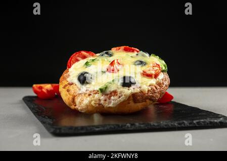 Fladenbrot Pepperoni Pizza mit Mozzarella-Käse, Salami, Tomatensauce, Pfeffer, Gewürzen. Italienische Pizza auf dunkelgrauem schwarzem Schieferhintergrund Stockfoto