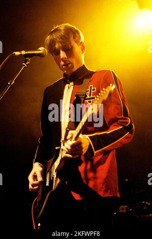 FRÜHE GIG, FRANZ FERDINAND, 2004: Ein sehr junger ALEXANDER KAPRANOS, Sänger und Gitarrist mit der schottischen Band FRANZ FERDINAND, der in der Woche der Veröffentlichung ihres gleichnamigen Debütalbums auf der NME Tour in Cardiff Students' Union am 8. Februar 2004 auf Tournee ging. Foto: ROB WATKINS. INFO: Franz Ferdinand ist eine 2002 gegründete schottische Rockband, die für ihren eingängigen, tanzbaren Post-Punk-Revival-Sound bekannt ist. Ihr Debütalbum „Franz Ferdinand“ und Hits wie „Take Me Out“ sorgten dafür, dass sie international berühmt wurden und einen bedeutenden Einfluss im Indie-Rock hatten. Stockfoto