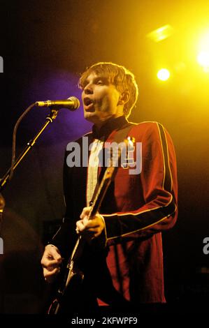 FRÜHE GIG, FRANZ FERDINAND, 2004: Ein sehr junger ALEXANDER KAPRANOS, Sänger und Gitarrist mit der schottischen Band FRANZ FERDINAND, der in der Woche der Veröffentlichung ihres gleichnamigen Debütalbums auf der NME Tour in Cardiff Students' Union am 8. Februar 2004 auf Tournee ging. Foto: ROB WATKINS. INFO: Franz Ferdinand ist eine 2002 gegründete schottische Rockband, die für ihren eingängigen, tanzbaren Post-Punk-Revival-Sound bekannt ist. Ihr Debütalbum „Franz Ferdinand“ und Hits wie „Take Me Out“ sorgten dafür, dass sie international berühmt wurden und einen bedeutenden Einfluss im Indie-Rock hatten. Stockfoto