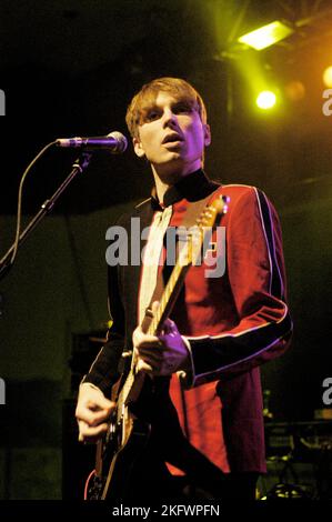 FRÜHE GIG, FRANZ FERDINAND, 2004: Ein sehr junger ALEXANDER KAPRANOS, Sänger und Gitarrist mit der schottischen Band FRANZ FERDINAND, der in der Woche der Veröffentlichung ihres gleichnamigen Debütalbums auf der NME Tour in Cardiff Students' Union am 8. Februar 2004 auf Tournee ging. Foto: ROB WATKINS. INFO: Franz Ferdinand ist eine 2002 gegründete schottische Rockband, die für ihren eingängigen, tanzbaren Post-Punk-Revival-Sound bekannt ist. Ihr Debütalbum „Franz Ferdinand“ und Hits wie „Take Me Out“ sorgten dafür, dass sie international berühmt wurden und einen bedeutenden Einfluss im Indie-Rock hatten. Stockfoto